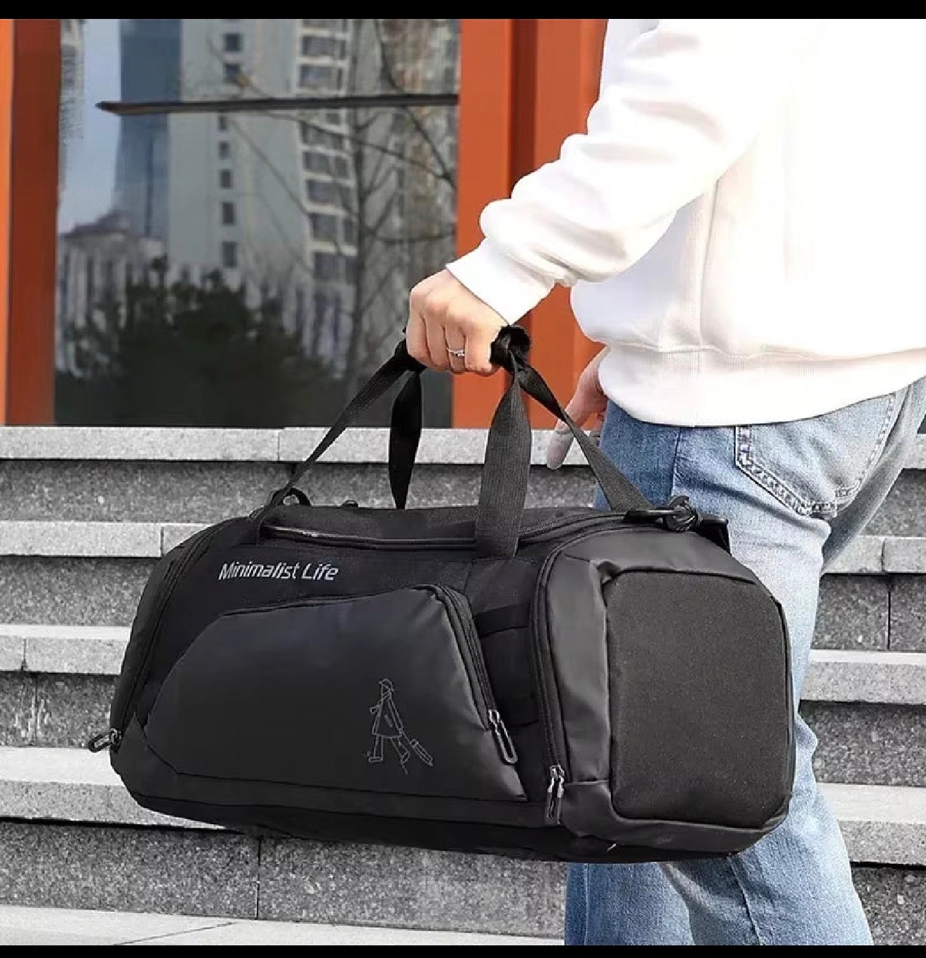 Person holding a black duffel bag with 'Minimalist Life' branding on steps.